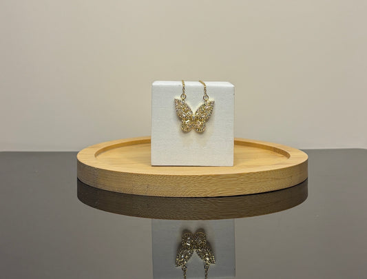 Butterfly-shaped necklace  on a white card with a wooden stand against a neutral background