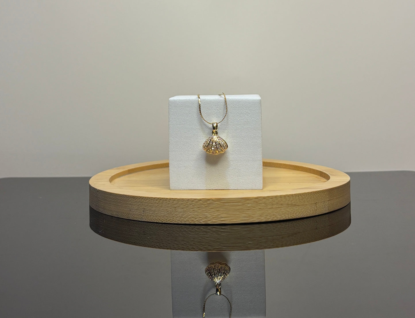 sea shell pendant on a white card on a wooden tray with a gray background