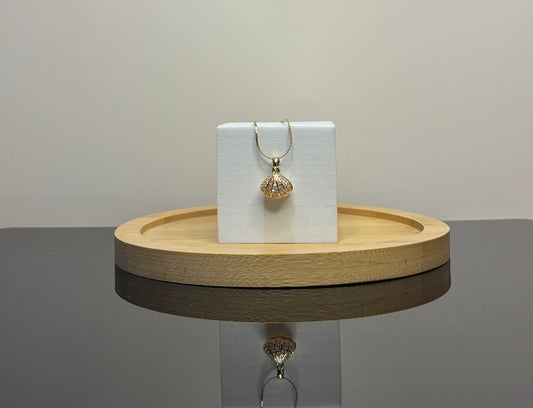 sea shell pendant on a white card on a wooden tray with a gray background