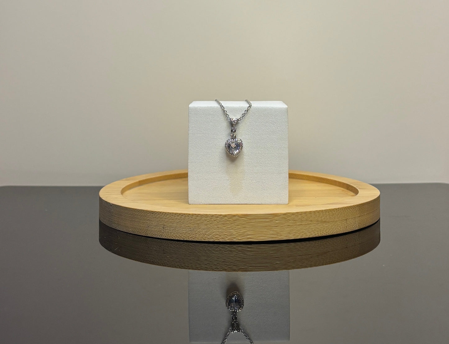 heart Necklace on a white box on a wooden stand with a neutral background