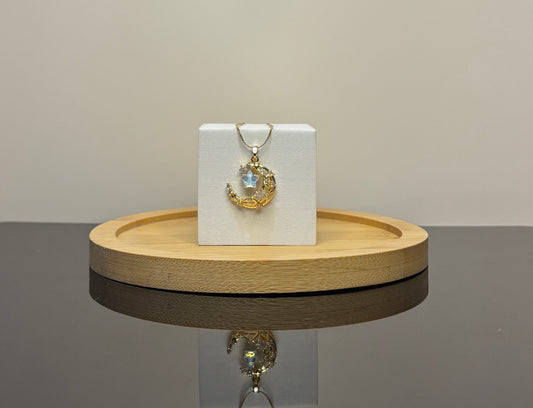 Gold necklace with a pendant on a white box on a wooden stand.