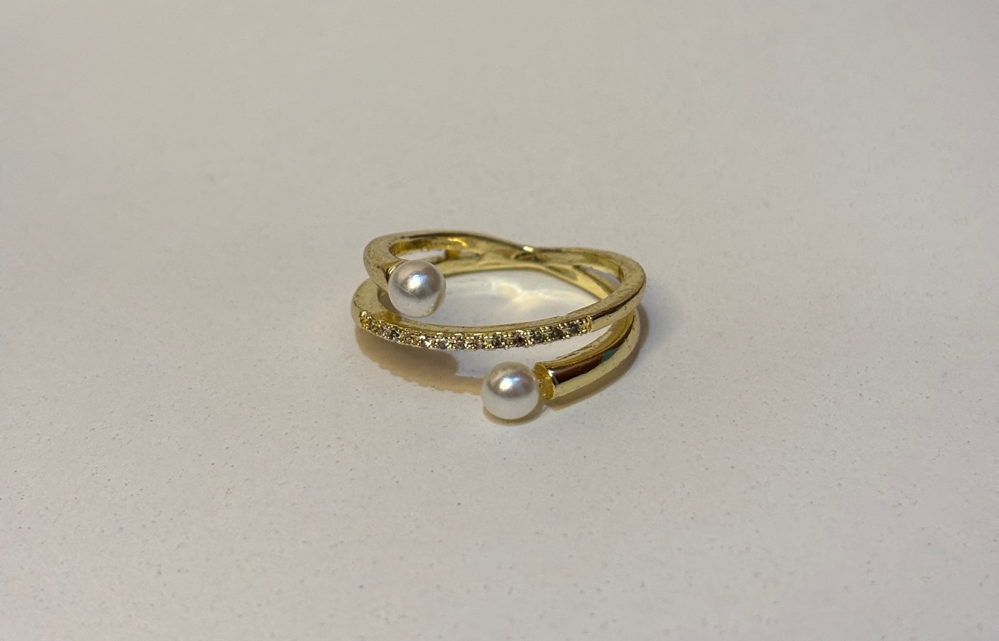 Gold ring with pearls on a light gray background