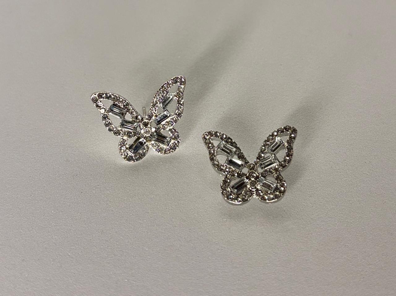 Butterfly-shaped earrings with gemstones on a light gray background