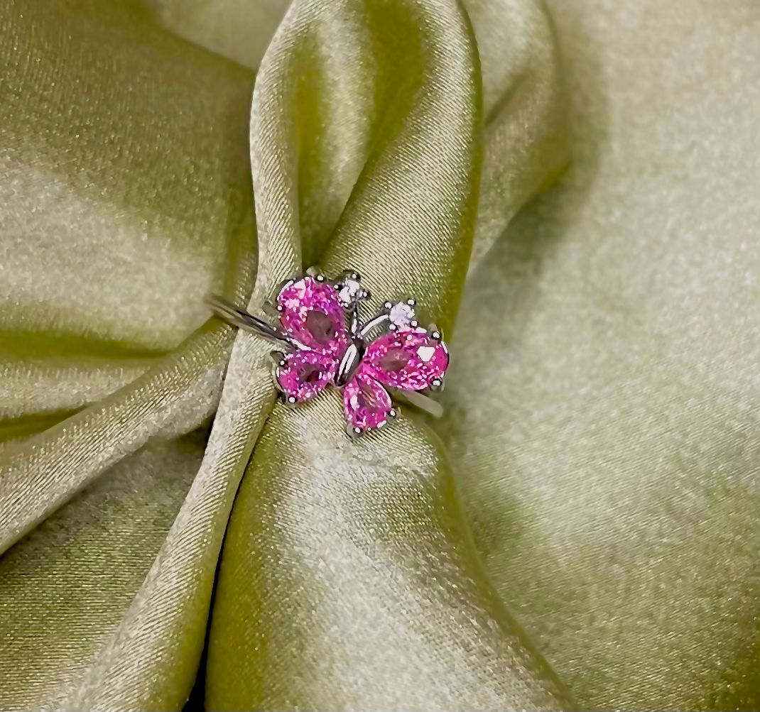 Pink butterfly-shaped gemstone ring on green fabric