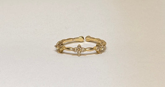 Gold ring with clover design on a light beige background