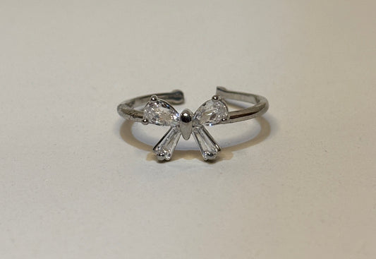 Silver bow-shaped ring with clear gemstones on a light gray background