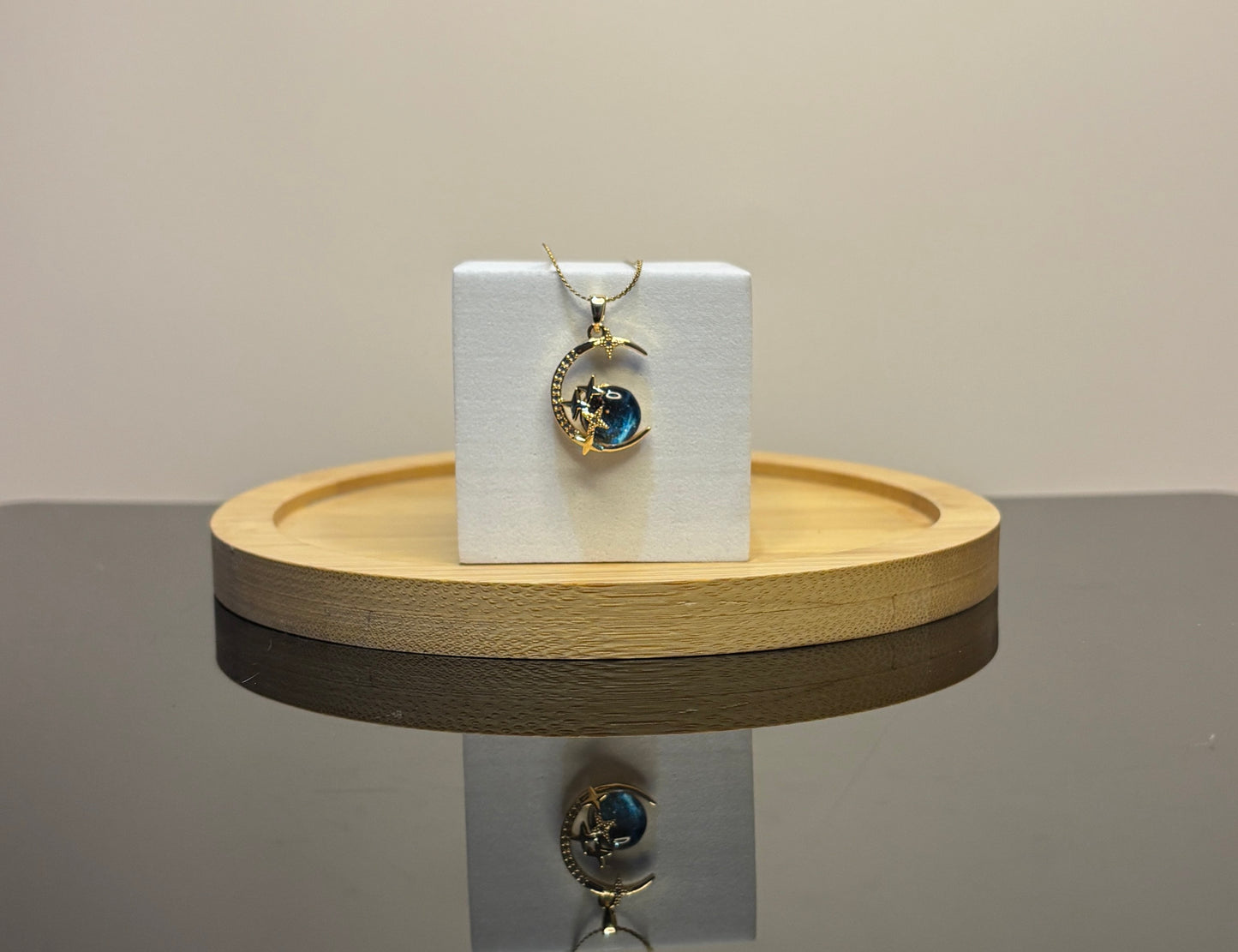 blue moon pendant on a white card with a wooden stand against a neutral background