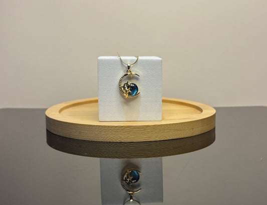 blue moon pendant on a white card with a wooden stand against a neutral background