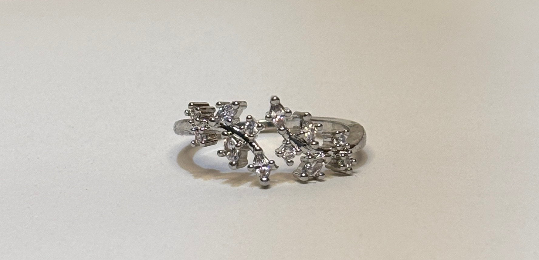 Silver ring with diamond-like stones on a light beige background