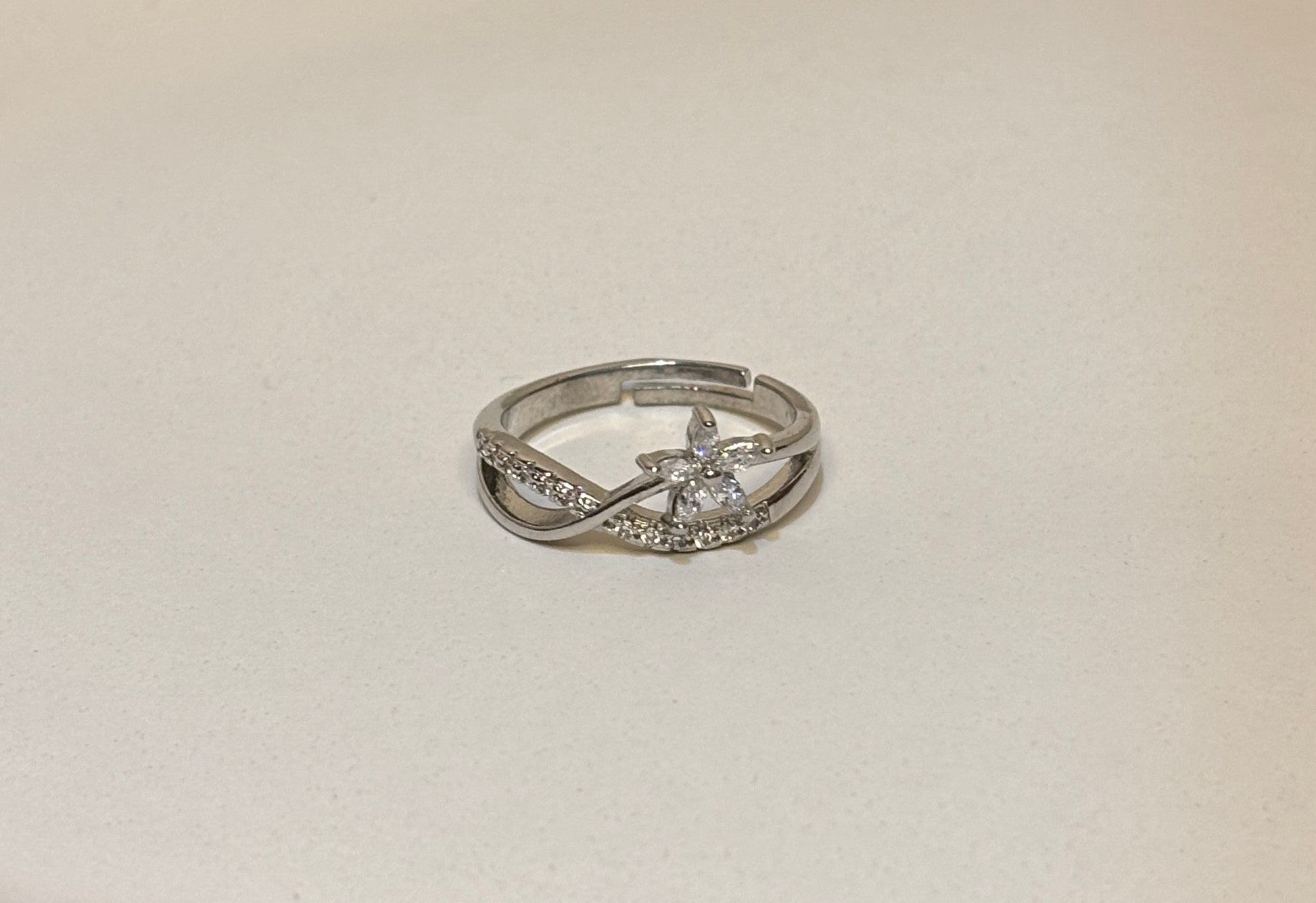 Silver floral ring with diamonds on a light beige background