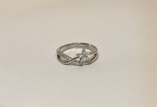 Silver floral ring with diamonds on a light beige background