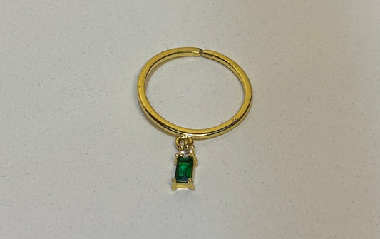 Gold ring with a green gemstone on a light gray background