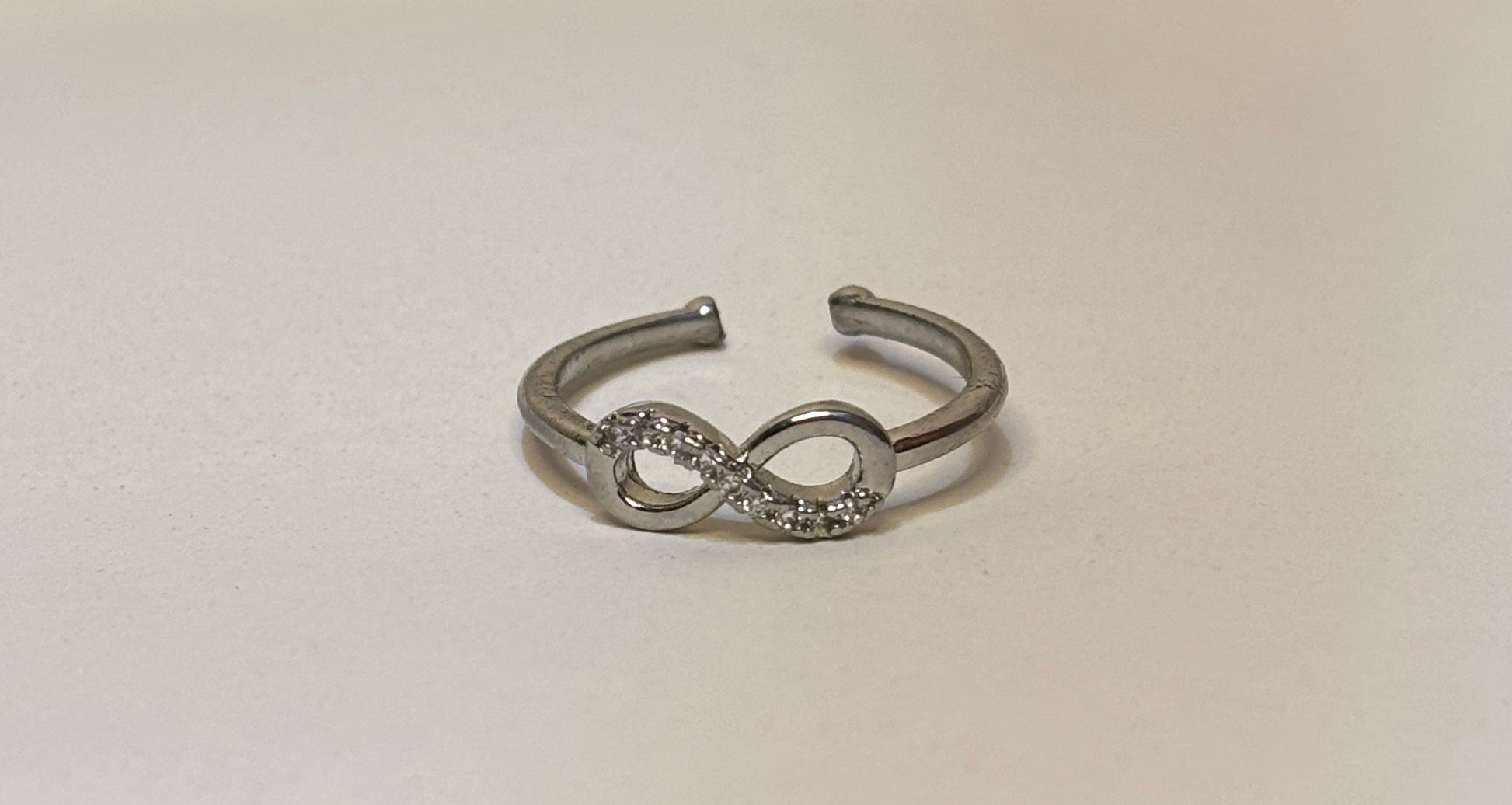 Silver infinity symbol ring on a light beige background