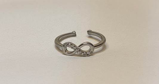 Silver infinity symbol ring on a light beige background