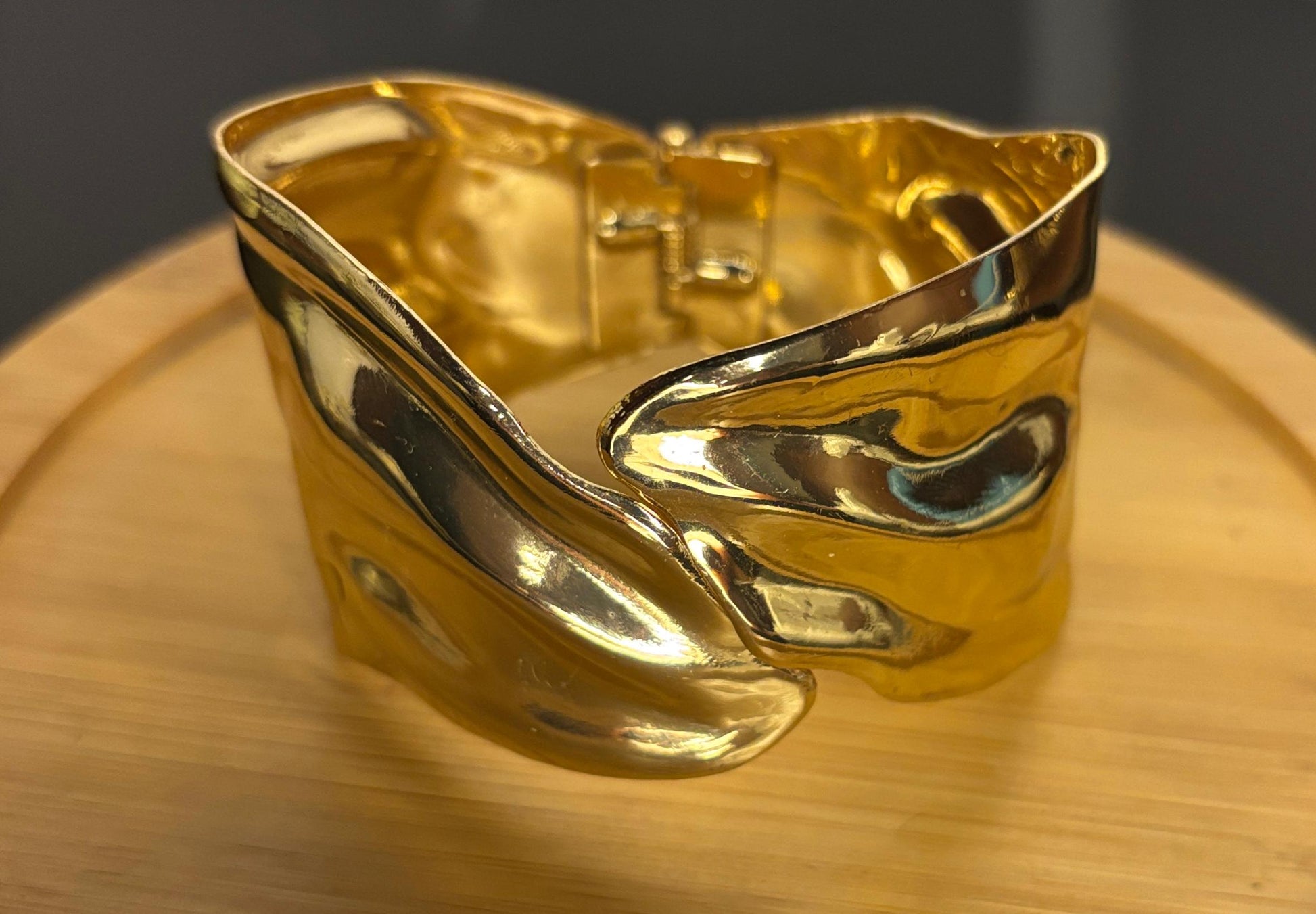 Gold bracelet on a wooden surface with a dark background
