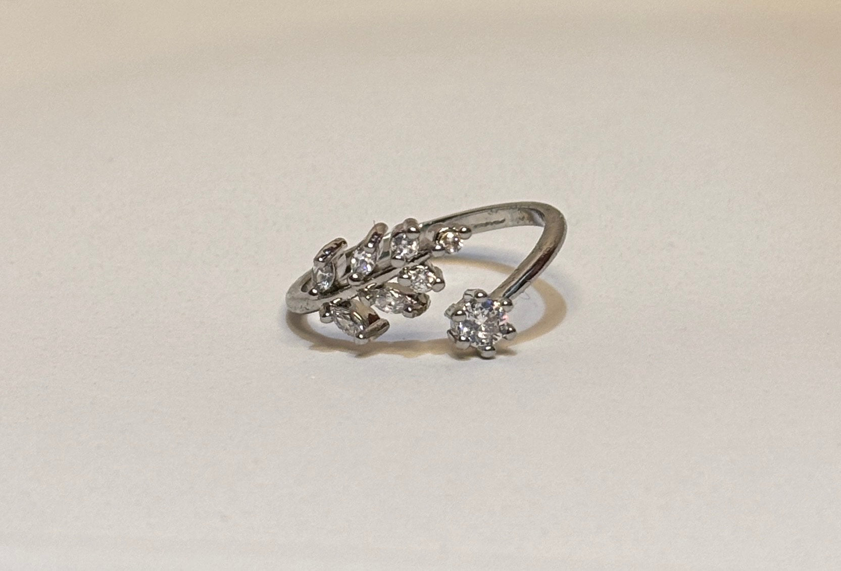 Silver ring with floral design on a light beige background