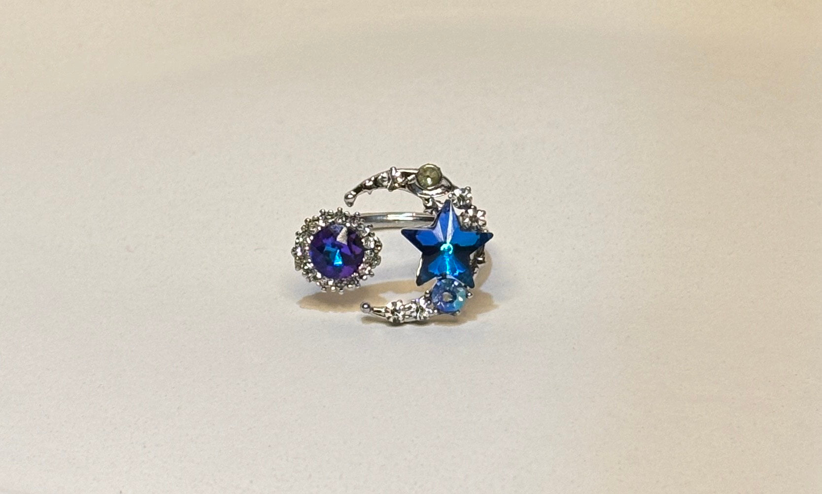 Silver moon star ring with blue gemstones on a white background
