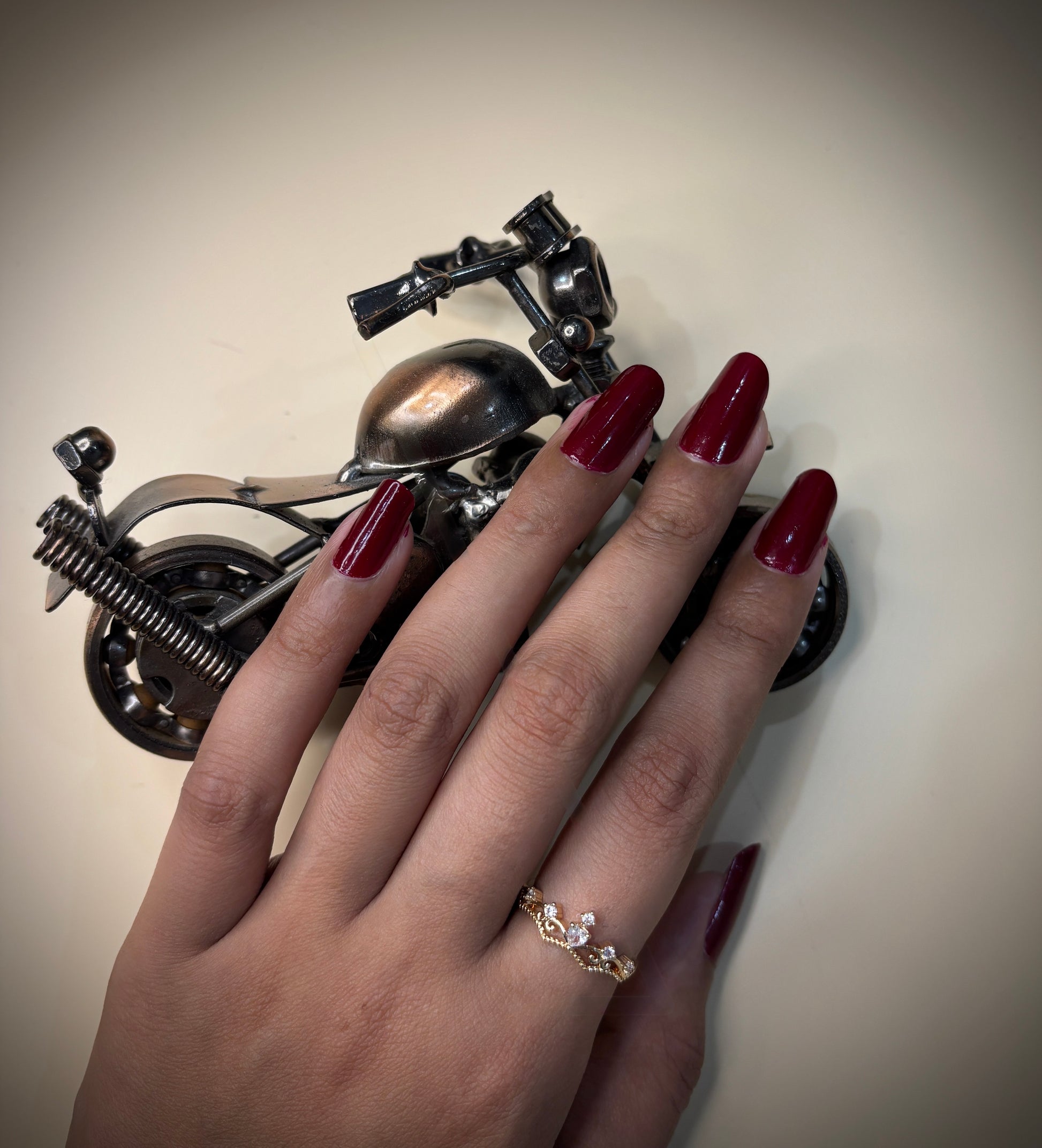 Hand with princess ring holding a motorcycle  on a neutral background