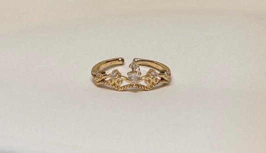 Gold ring with intricate crown design on a light gray background