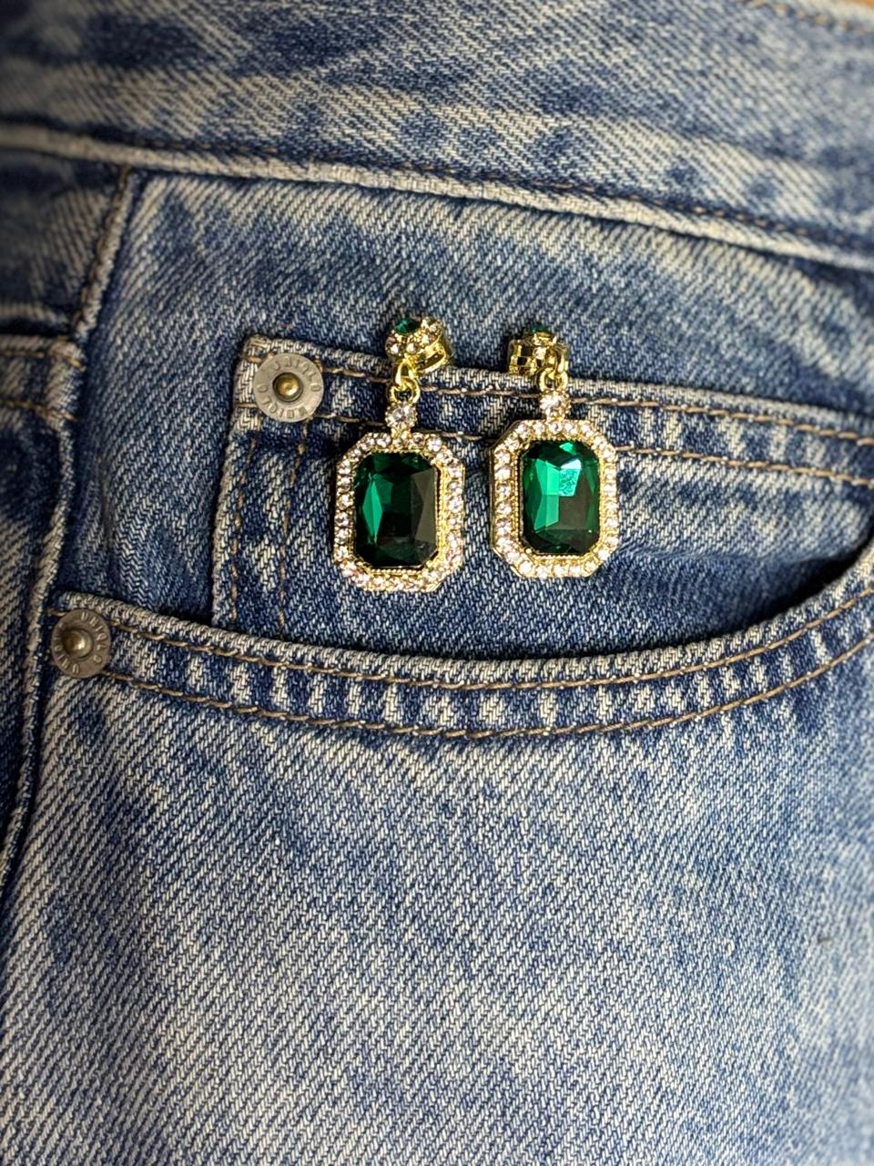 Green gemstone earrings on a blue denim background