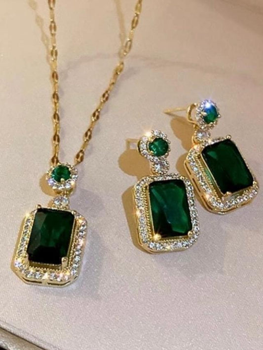 Green gemstone earrings and necklace with gold accents on a light background