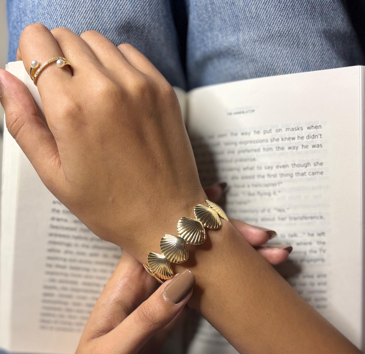 Hand wearing a gold bracelet on a book background