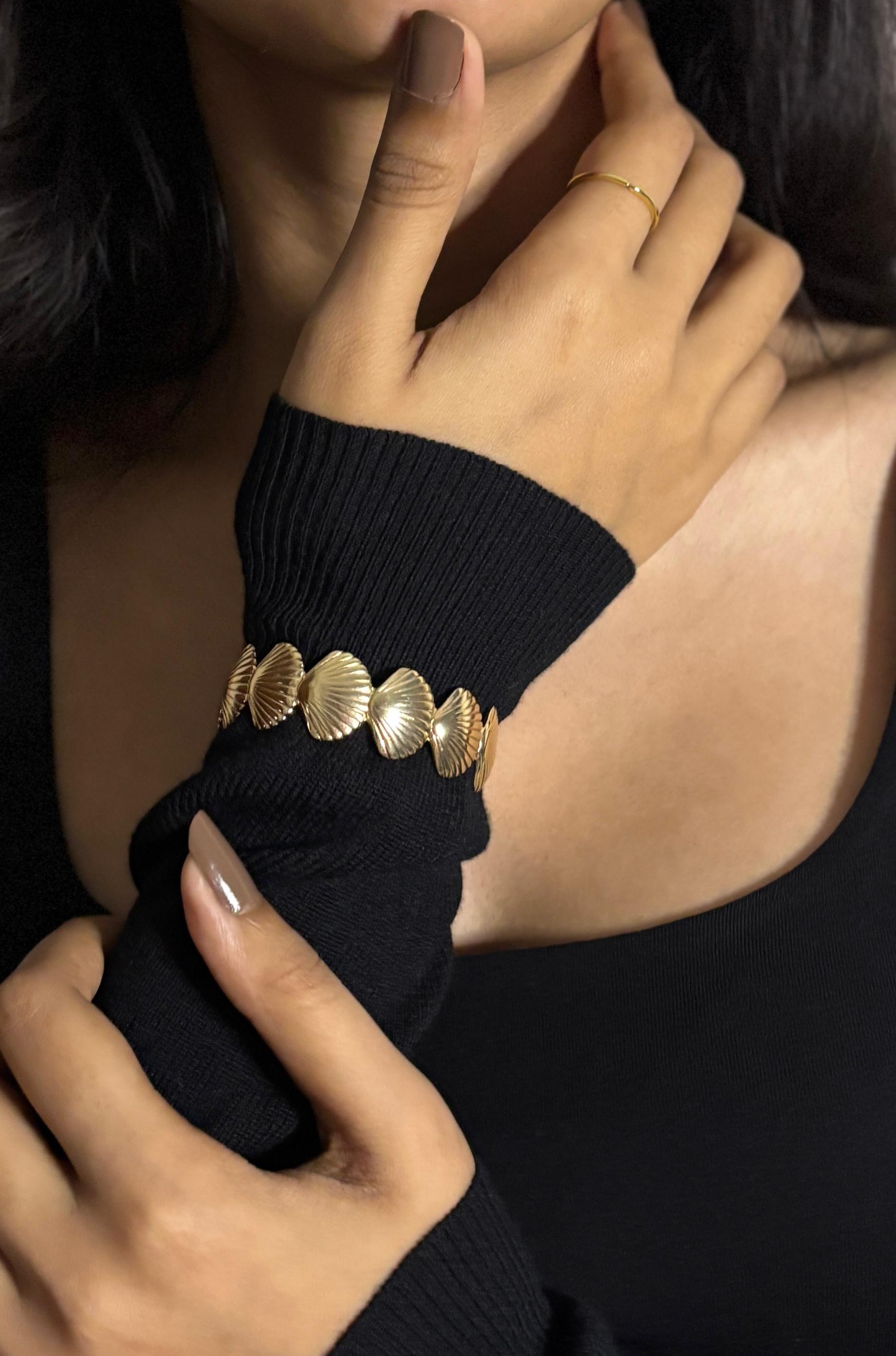 Close-up of a person wearing a gold bracelet on a black sleeve.
