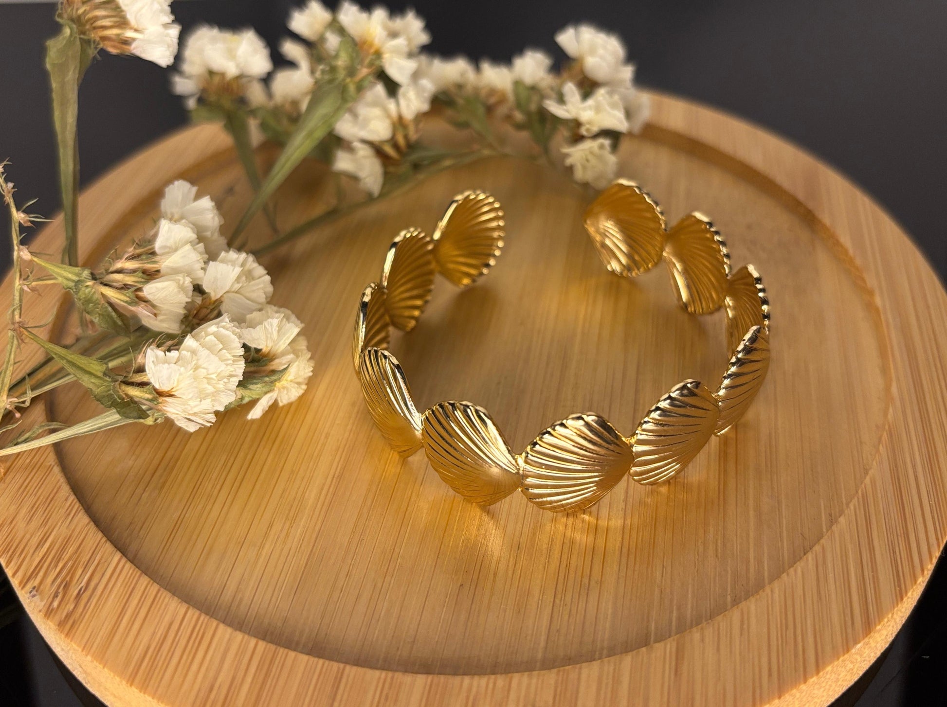Gold bracelet on a wooden surface with white flowers