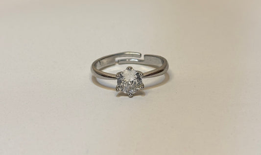 Silver solitaire ring with a diamond on a beige background