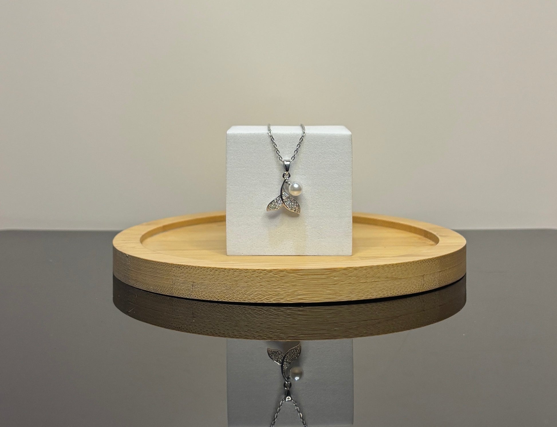 mermaid Pearl necklace on a white box with a wooden stand on a gray surface