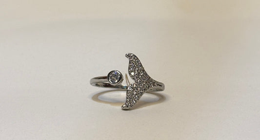 Silver mermaid tail ring with gemstones on a light beige background