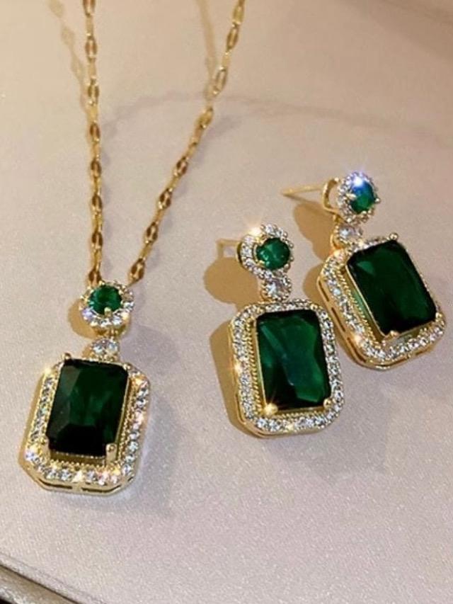 Green gemstone earrings and necklace with gold accents on a light background